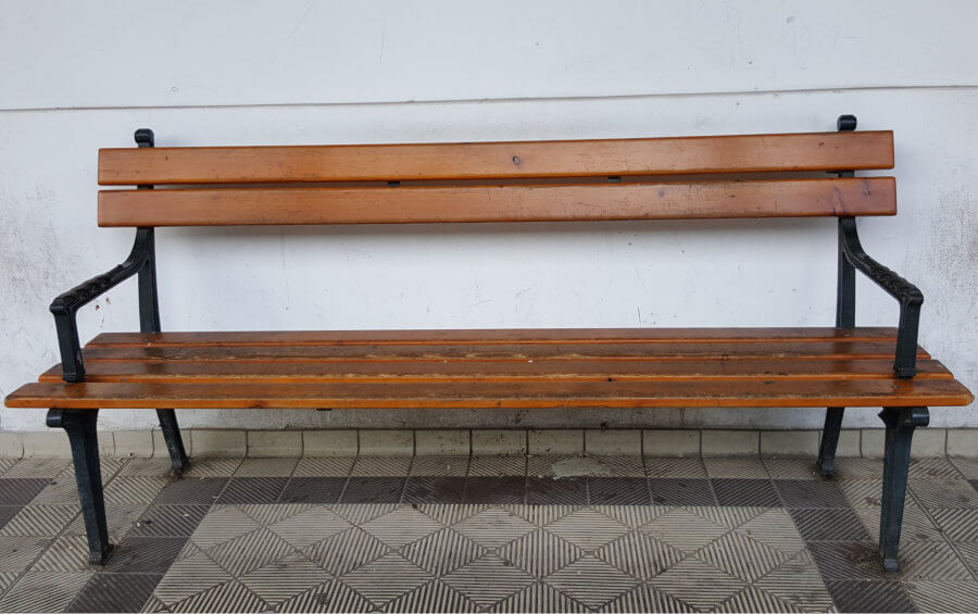 Sitzbank mit braungestrichenen Holzlatten, Seitenteile schlicht und aus Gusseisen.