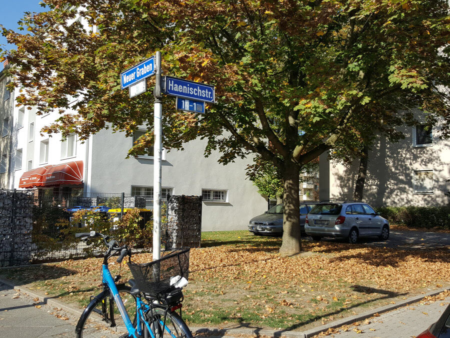 Ecke Neuergraben /Haenischstraße - Blick auf Straßentafeln mit geparktem Fahrrad, dahinter Rasenstück und Wohnsiedlung.